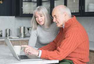 Couple sitting in kitchen looking at laptop
