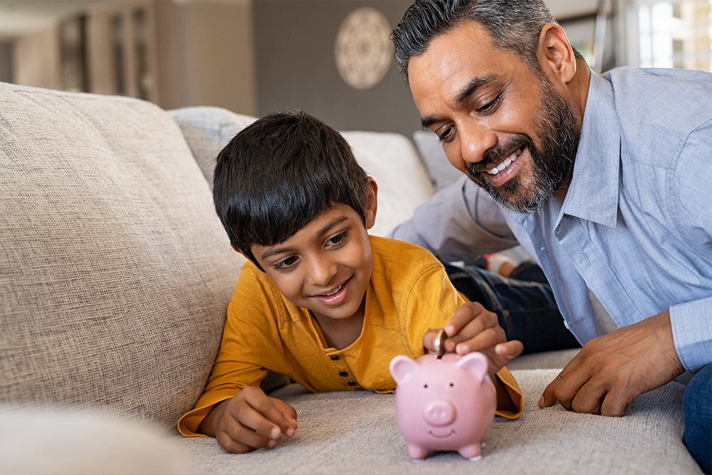 A father and son putting money into a piggybank.